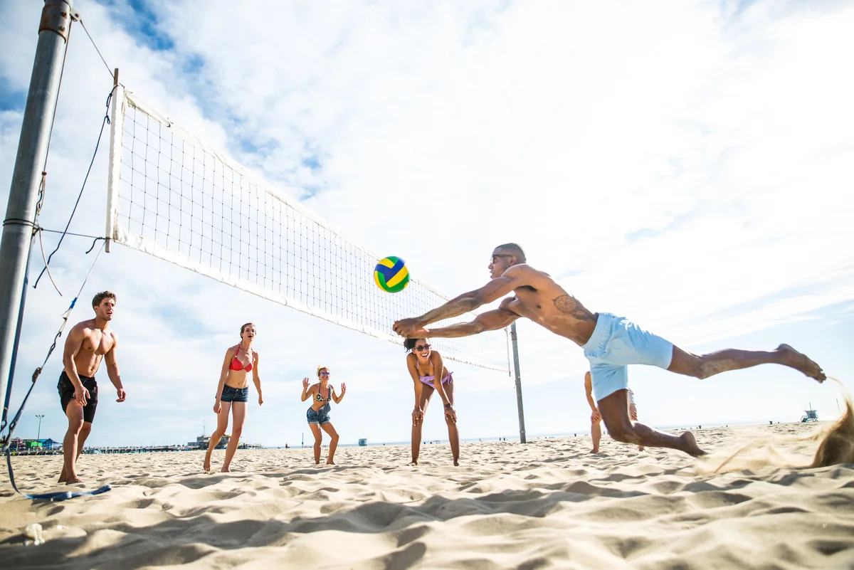 Przyjaciele grający w siatkówkę plażową Grupa przyjaciół grająca w siatkówkę plażową